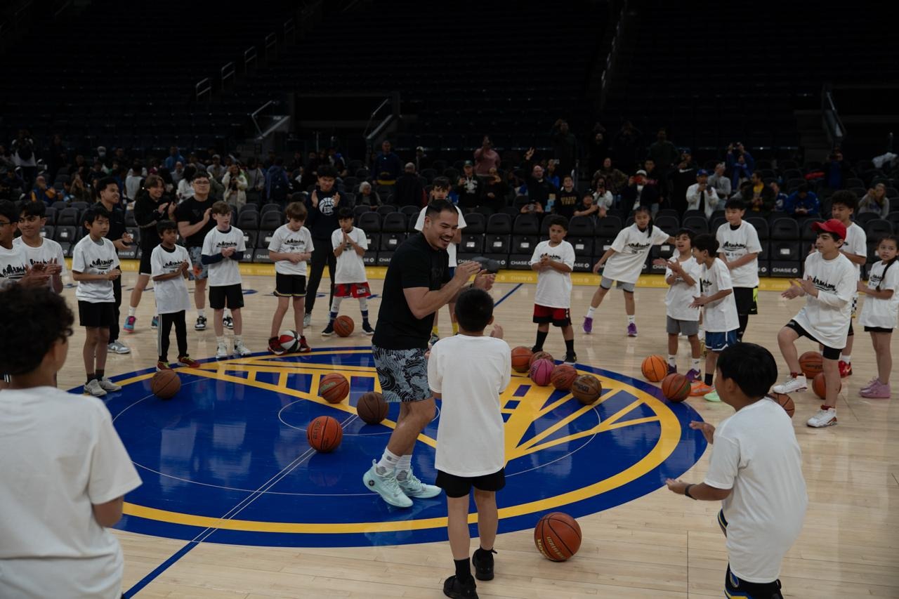 Kyle Travis coaching young athletes at Chase Center on the Warriors logo